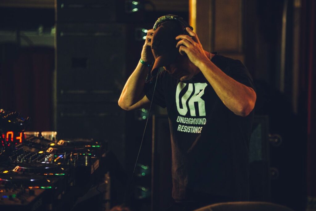 Greg about to put headphones on and lock in. Wearing a black tshirt with Underground Resistance text.